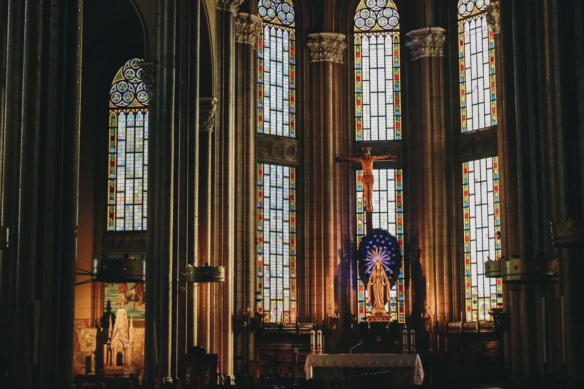 Interior de catedral católica com vitrais coloridos representando os tempos litúrgicos