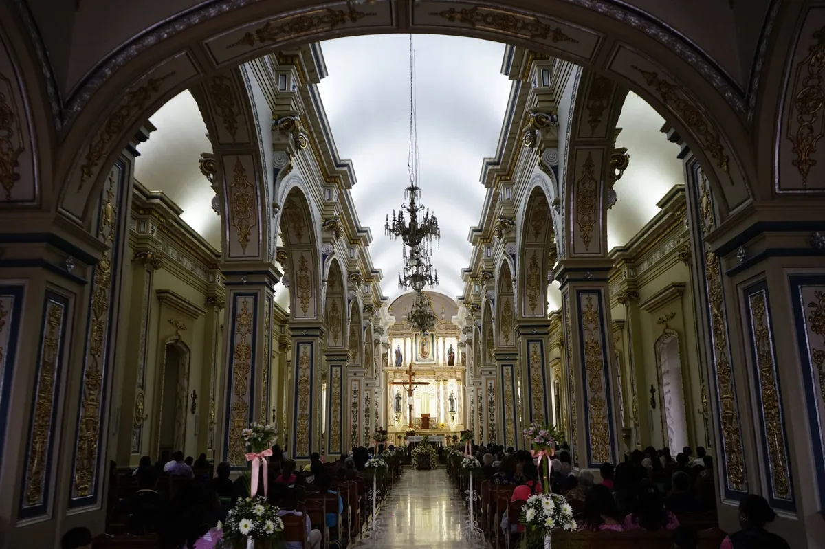 Fiéis reunidos no interior de uma catedral católica, representando a comunidade que acolhe a criança no batismo