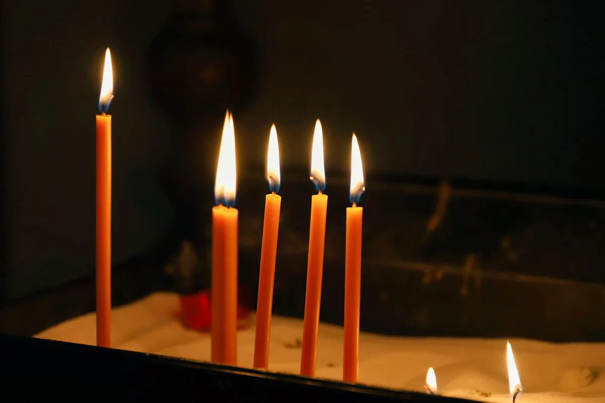 Velas acesas na penumbra da igreja, simbolizando a luz da consciência e a oração