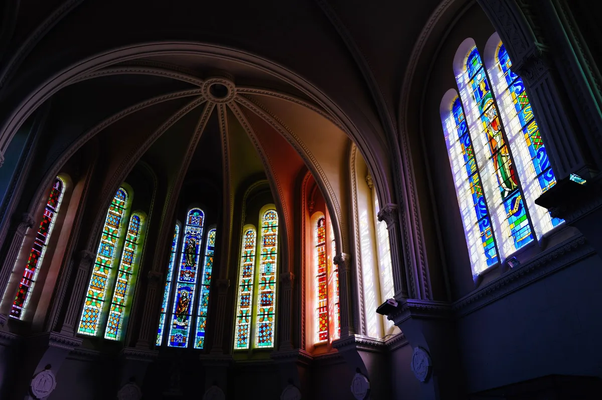 Interior de catedral com vitrais coloridos iluminados pela luz natural