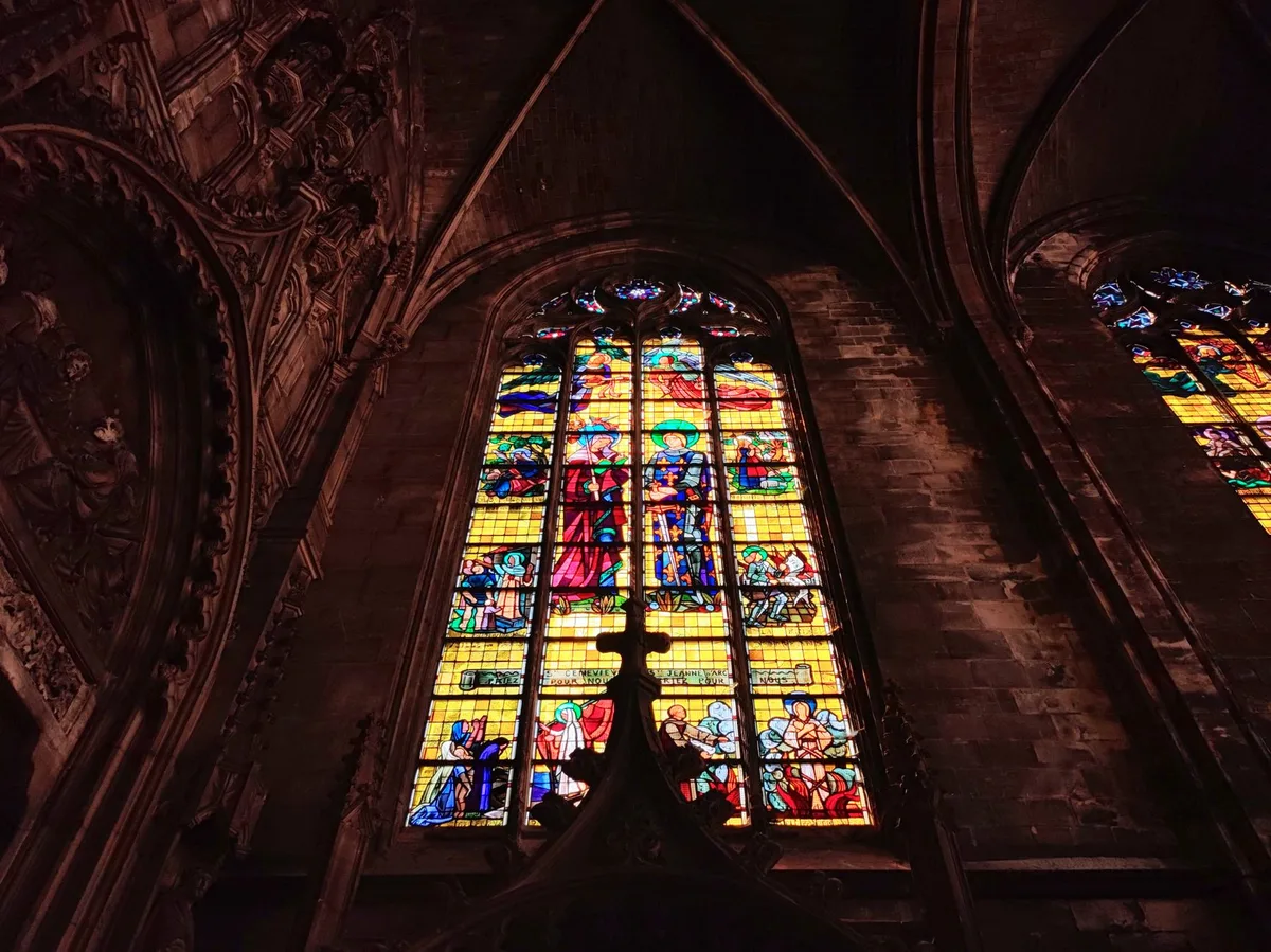 Interior de catedral católica com vitrais coloridos iluminados, representando a luz da Ressurreição