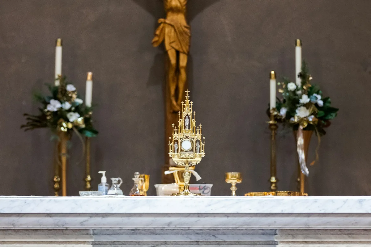 Cruz de madeira simples sobre o altar dentro de uma igreja católica iluminada de forma suave.