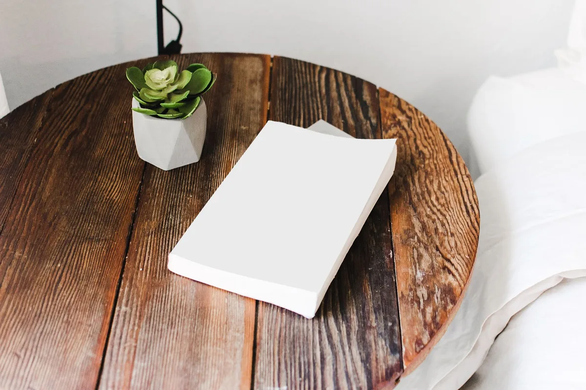 Vela acesa e livro de orações sobre a mesa de madeira, ambiente acolhedor para a oração da noite
