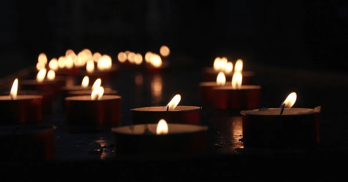 Velas votivas acesas em fileiras dentro de uma igreja, representando intenções de oração