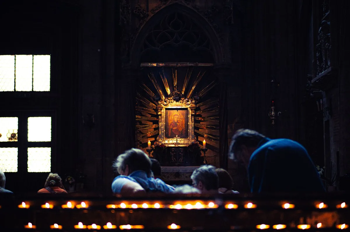 Fiéis reunidos em oração dentro de uma catedral, expressando a devoção da peregrinação
