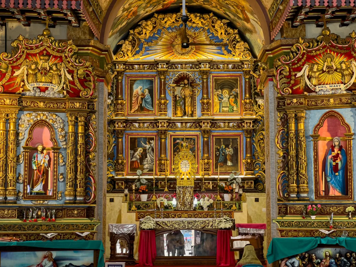 Interior de igreja católica com altar decorado e pinturas religiosas