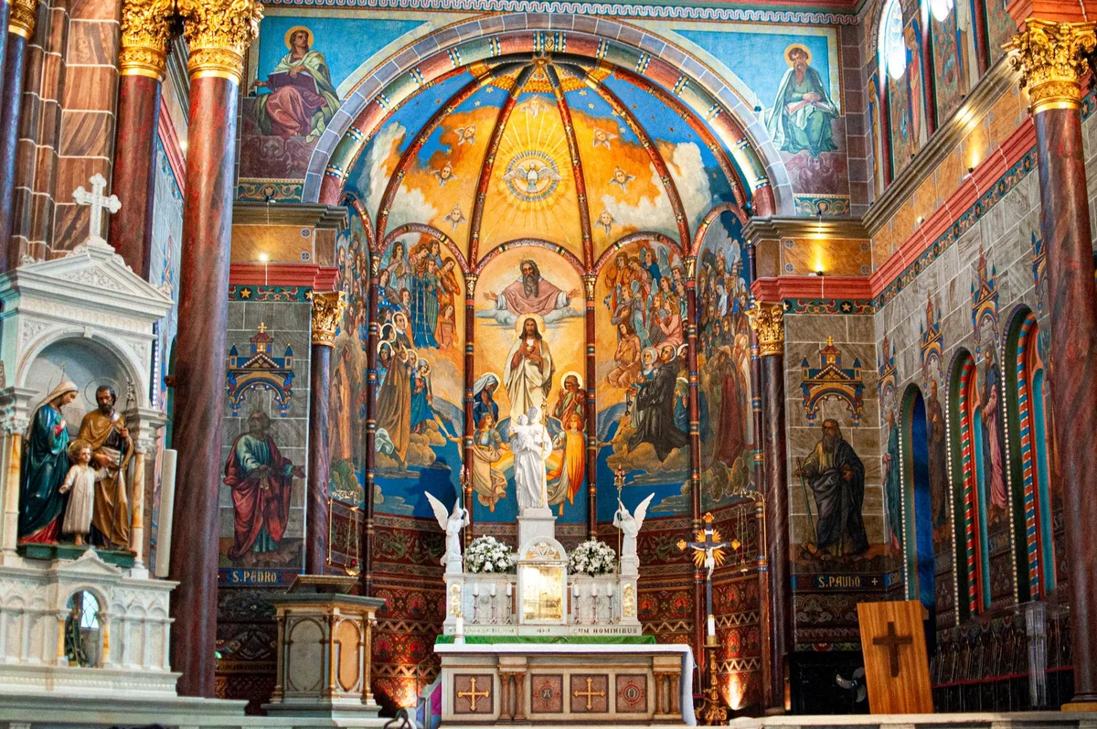 Interior de igreja católica com decoração dourada e altar ornamentado