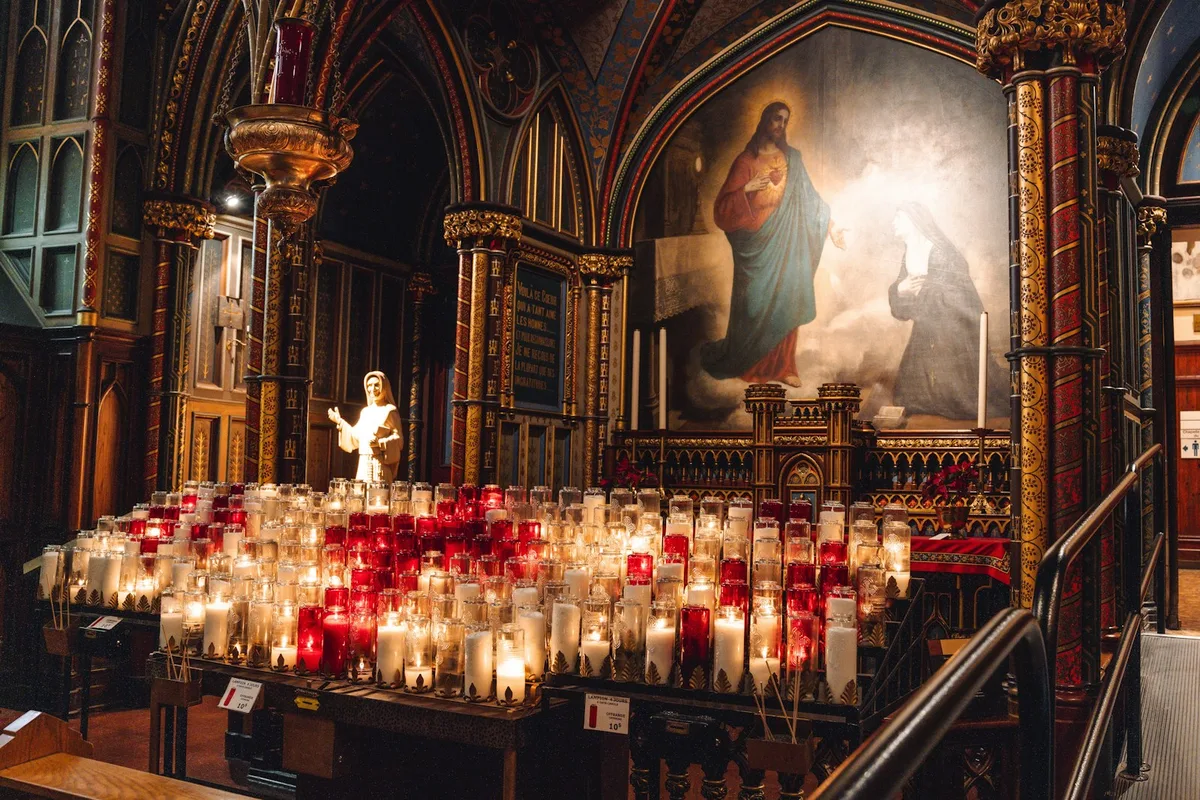 Velas votivas acesas em uma igreja, representando a devoção aos santos padroeiros