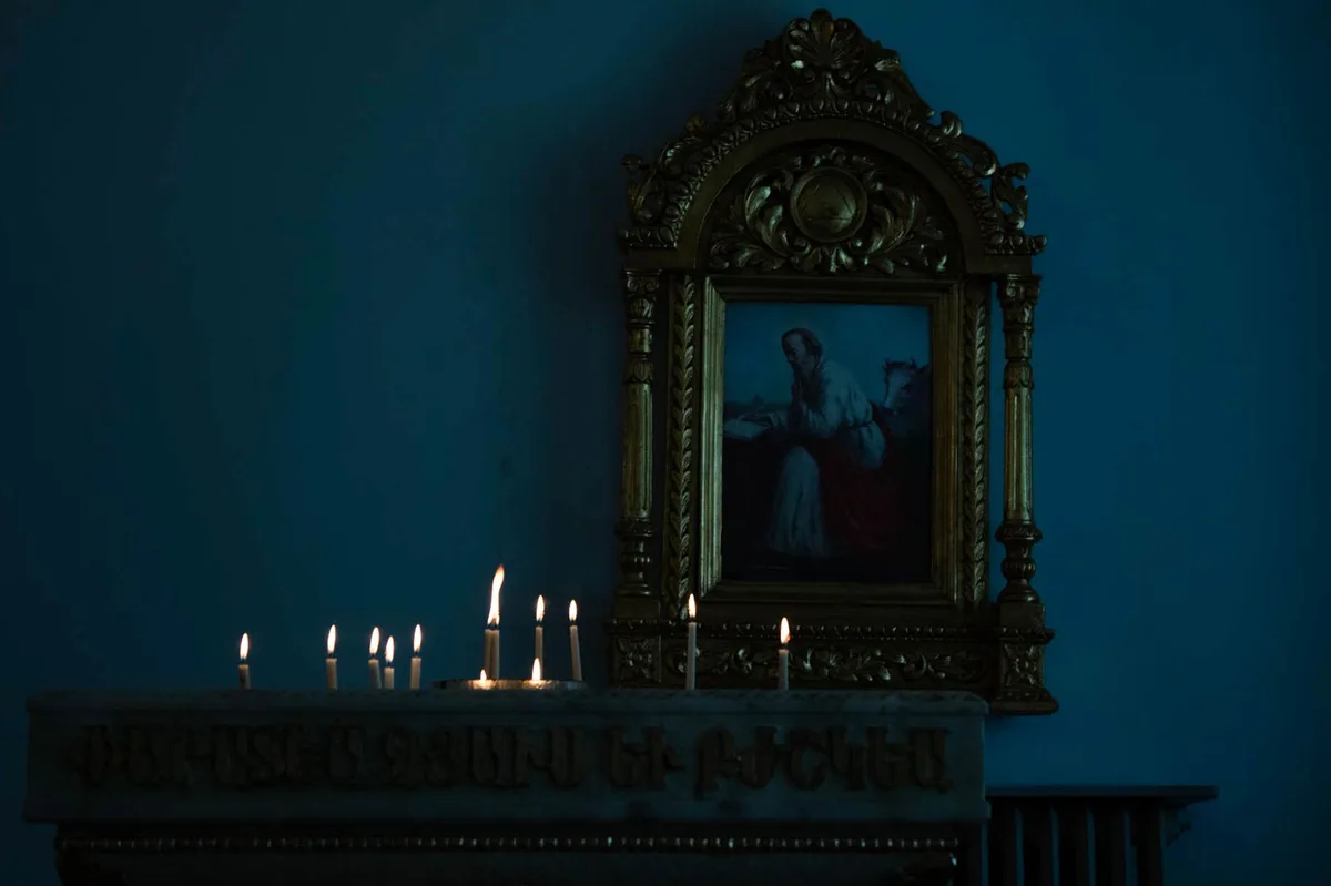 Velas votivas acesas em fileiras na igreja, simbolizando memória e oração