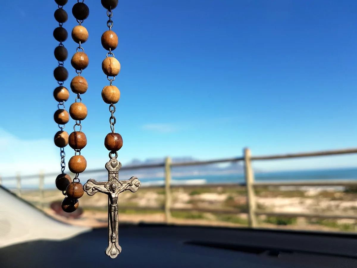 Terço de madeira com crucifixo sobre superfície escura, simbolizando a oração da Divina Misericórdia